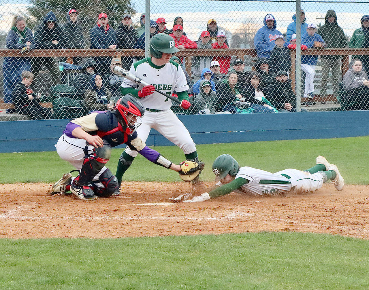 Port Angeles’ Alex Angevine scores on a steal of home in the first inning against Sequim at Civic Field on Tuesday, getting in just under the tag of Wolves’ catcher Lincoln Bear. The batter is Port Angeles’ Elijah Flodstrom. (Dave Logan/for Peninsula Daily News)