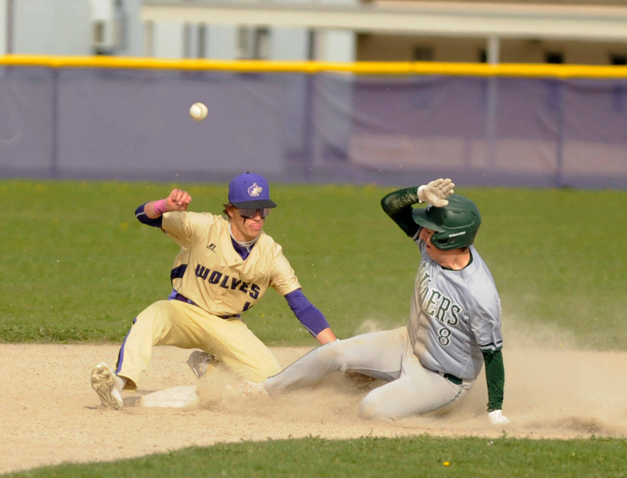 Michael Dashiell/Olympic Peninsula News Group Sequim’s Bryan Laboy, left, looks to put the tag on Port Angeles’ Colton Romero in the third inning of an Olympic League match-up on April 13. The Roughriders scored five innings en route to a 12-2 win in Sequim.