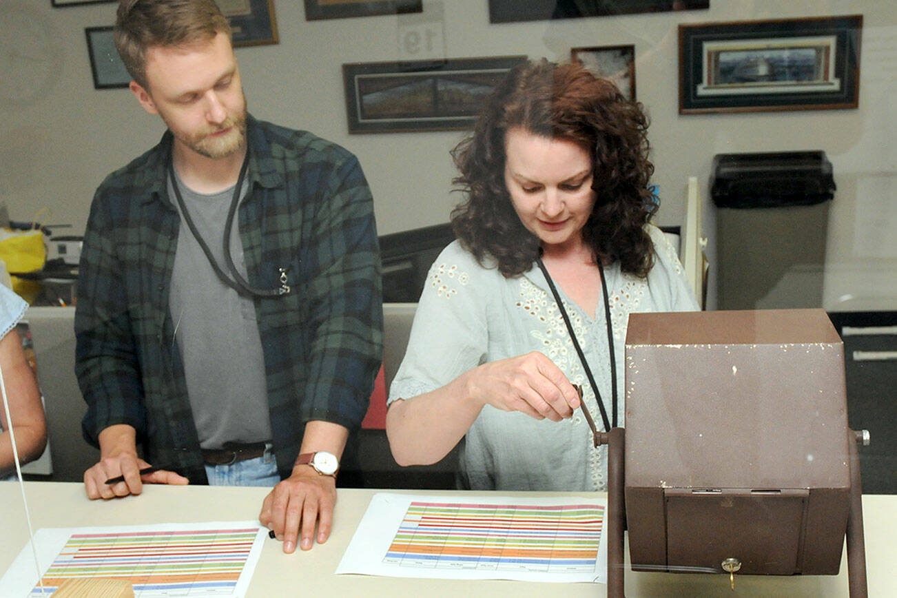 KEITH THORPE/PENINSULA DAILY NEWS
Clallam County election assistant Gretchen Weeks, right, spins a tumbler containing the names of candidates a county voter registration coordinator Joshua Hart records the results during a lot drawing for candidate positions on the ballot on Friday at the county courthouse in Port Angeles.