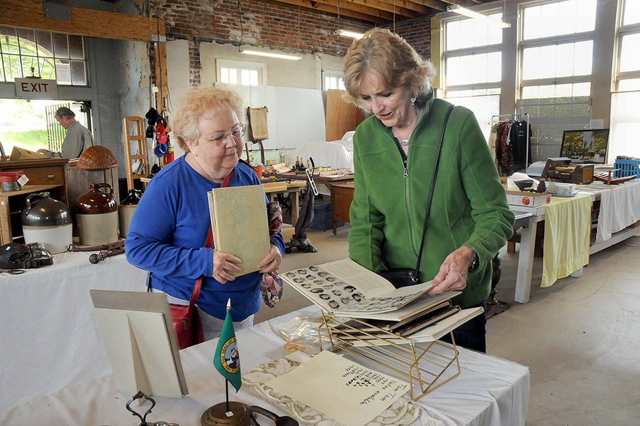 Maureen Sandison, left, and Valle Nevaril, both of Port Angeles, examine high school year books on sale at the North Olympic History Center’s Vintage Sale on Saturday at the former Lincoln School in Port Angeles. The sale, which included collectables, vintage clothing, tools and other items, was designed to benefit the center’s programs and operations. (Keith Thorpe/Peninsula Daily News)