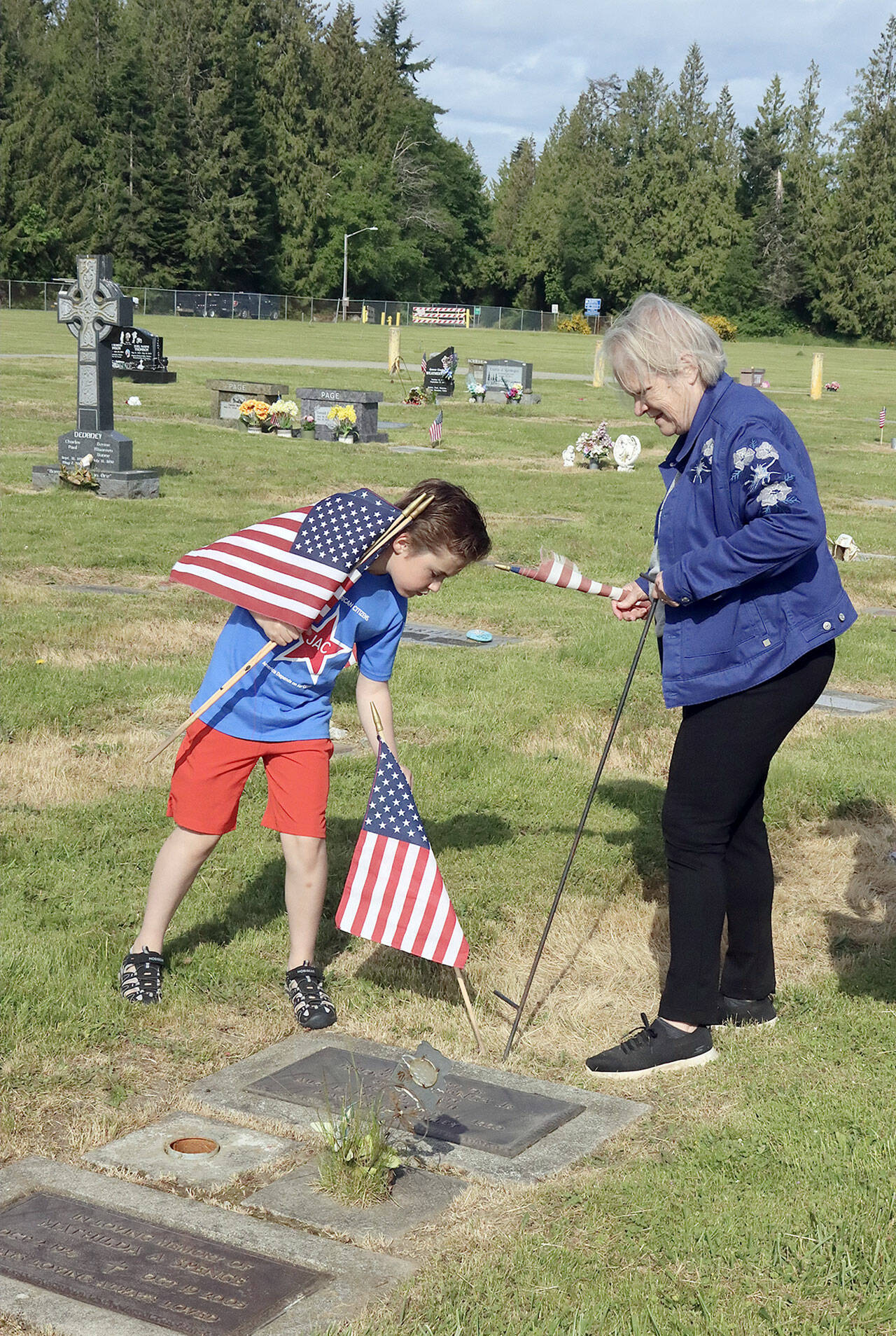 Samuel Jones, 9, and Grace Kauffman help place hundreds of flags on graves of deceased veterans at Ocean View Cemetery early Saturday morning. The tradition this year was led by the Daughters of the American Revolution organization. (Dave Logan/for Peninsula Daily News)