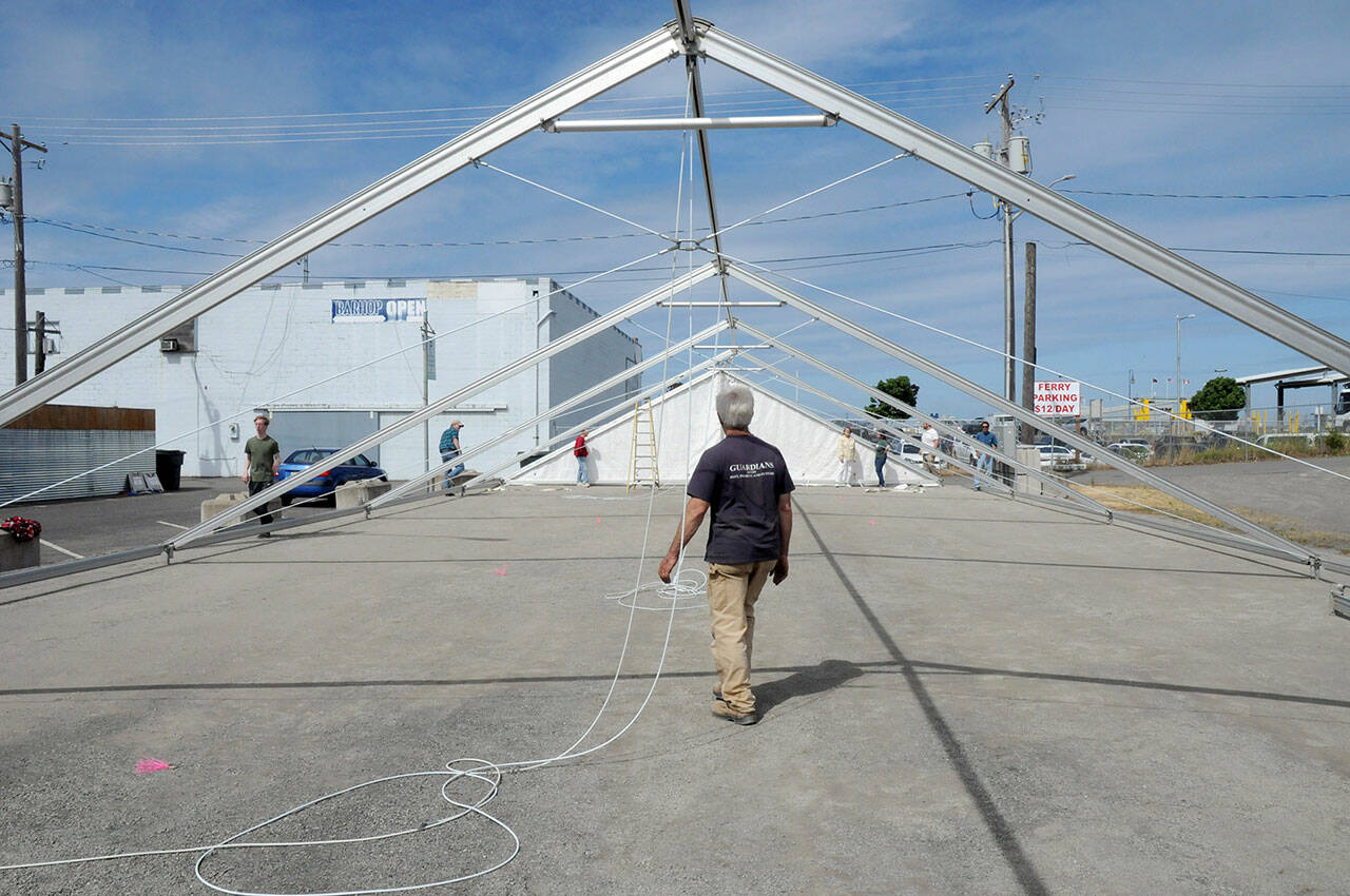 Steve Hargis, a board member of the Port Angeles Chamber of Commerce, directs the alignment of an events tent on Thursday that will cover a temporary roller skating rink in downtown Port Angeles. (KEITH THORPE/PENINSULA DAILY NEWS)