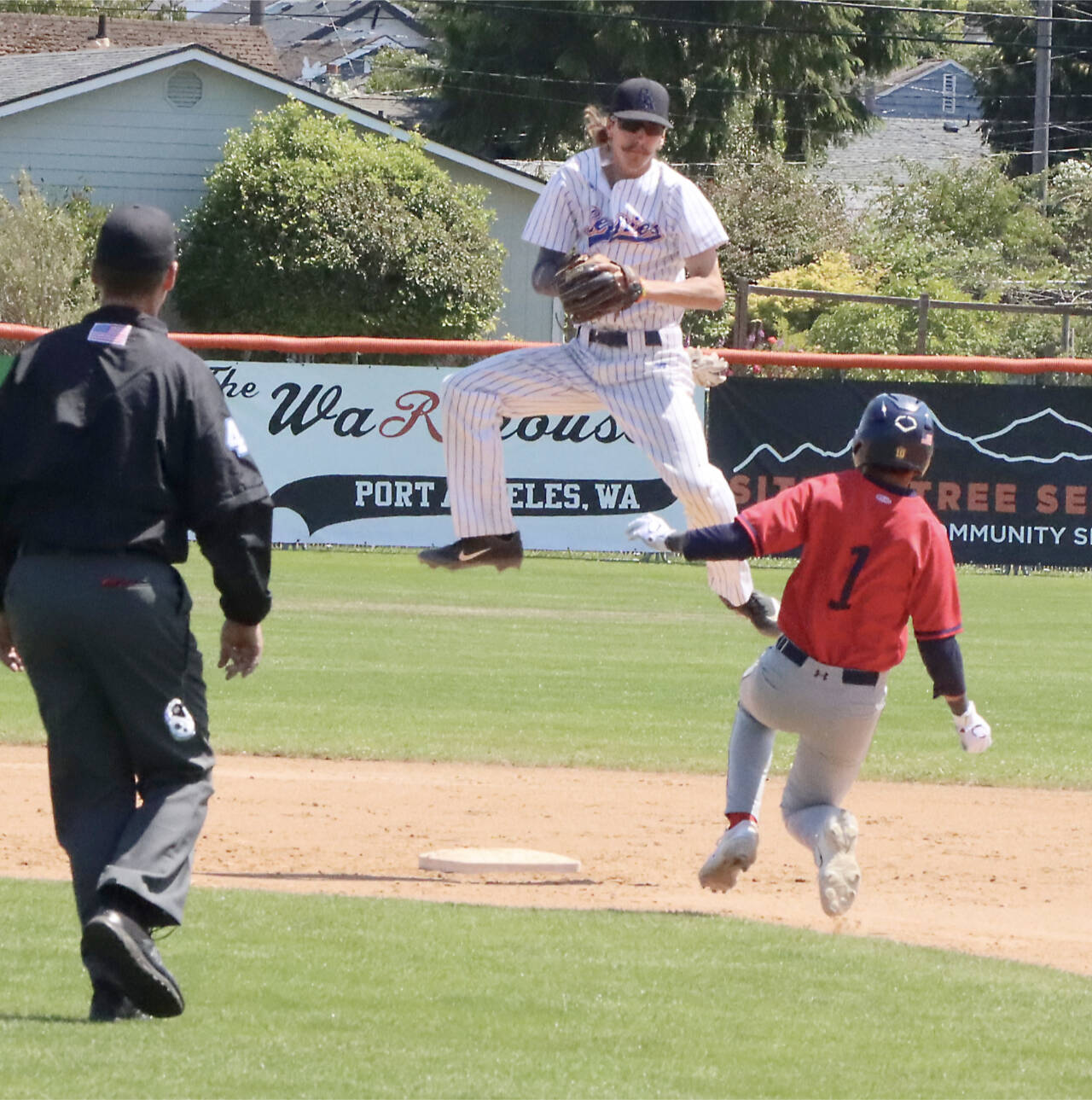 Port Angeles Lefties second baseman Roberto Nunez jumps to catch a throw but isn’t able to punch out Kelowna baserunner Eddie Fines on Sunday at Civic Field. (Dave Logan/for Peninsula Daily News)