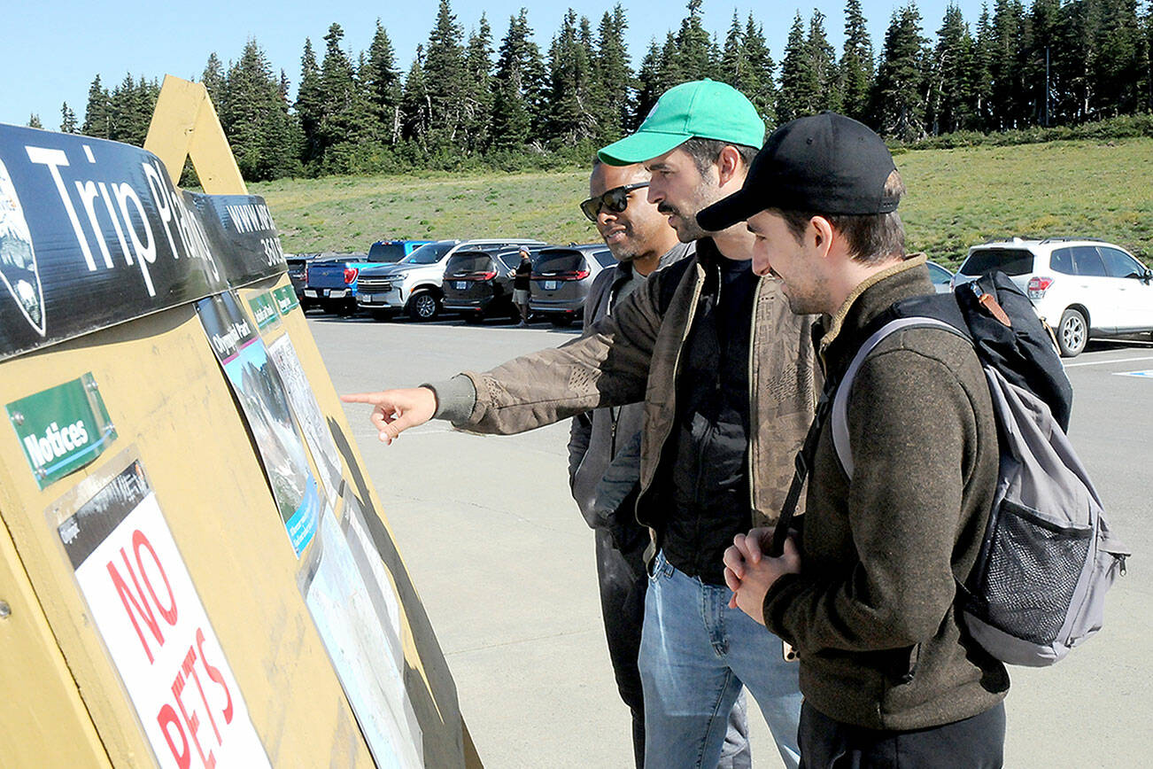 Olympic National Park visitors, from left, Nelson Nunez, Mateo Sancho and Albert Martinez, all from New York City, look at an information board at Hurricane Ridge after the area was reopened to the public on Tuesday. (Keith Thorpe/Peninsula Daily News)