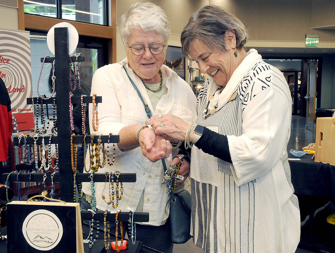 Carol Pearson of Sequim-based Lizzie Betz Jewelry assists Maureen Kennedy of Port Angeles with a bracelet during Saturday’s Rain Shadow Artisans Fair at the Dungeness River Nature Center in Sequim. The event brought together more than a dozen local crafters with the opportunity to market their wares. (Keith Thorpe/Peninsula Daily News)