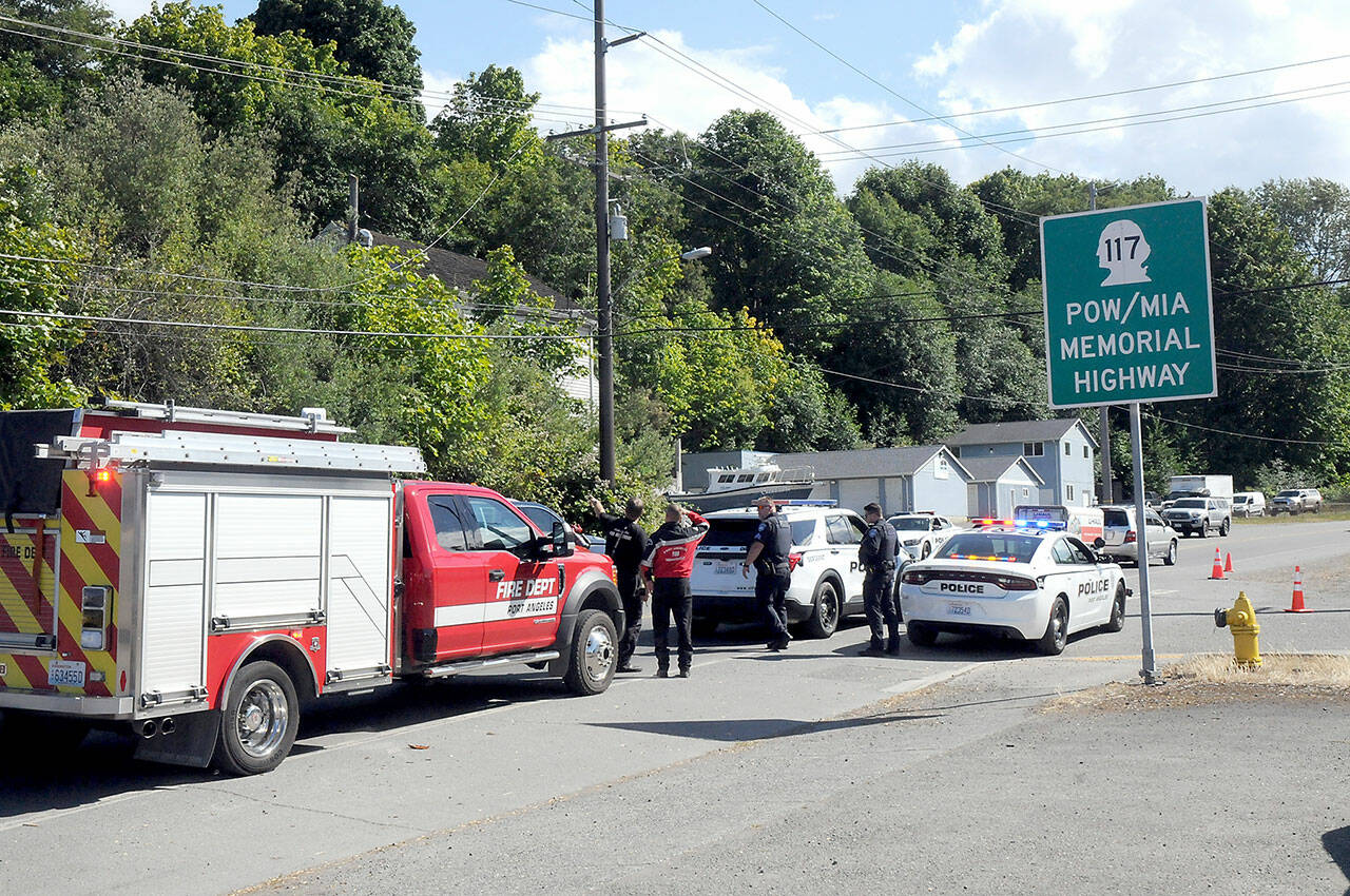 Port Angeles police and firefighters examine a utility pole and a downed powerline along the Tumwater Truck Route at Third Street that disrupted traffic and caused power outages on Wednesday afternoon. (Keith Thorpe/Peninsula Daily News)