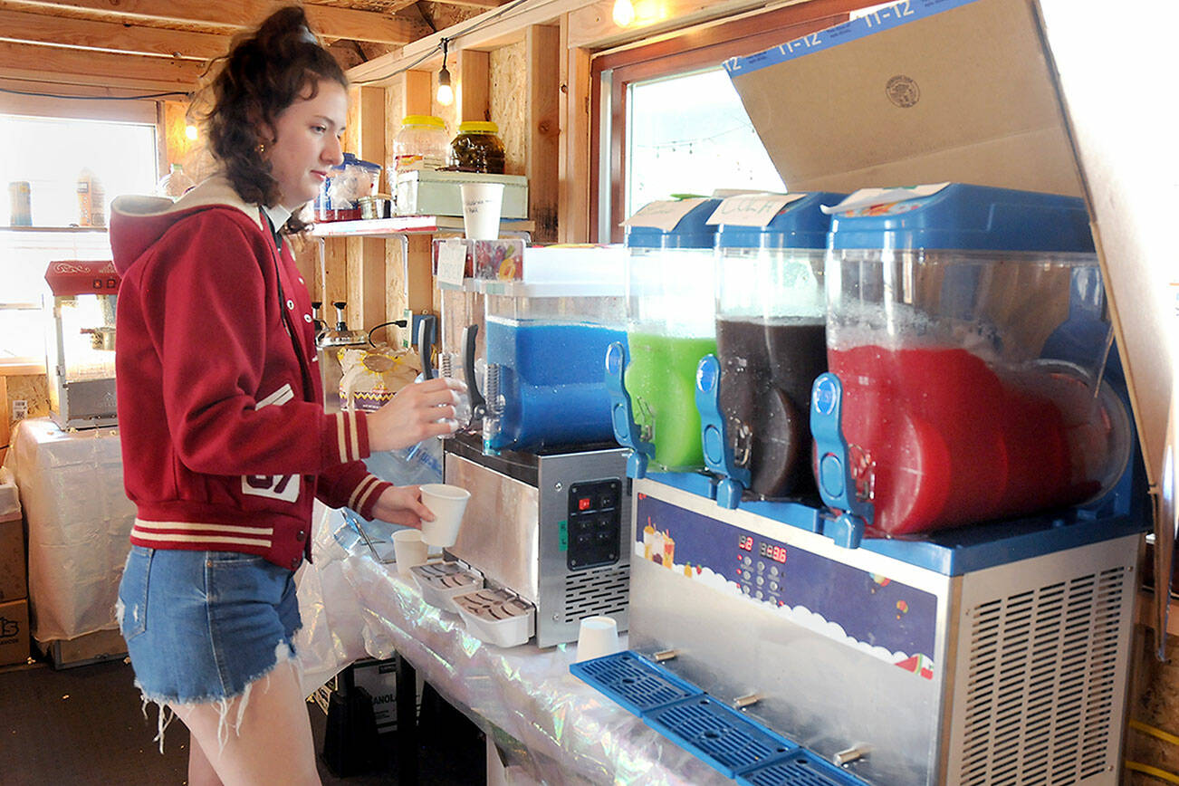 Olympic Skate Village manager Shanzi Cosgrove fills a slushy order at the village’s Snack Shack next to the temporary roller skating rink on Friday in downtown Port Angeles. (Keith Thorpe/Peninsula Daily News)