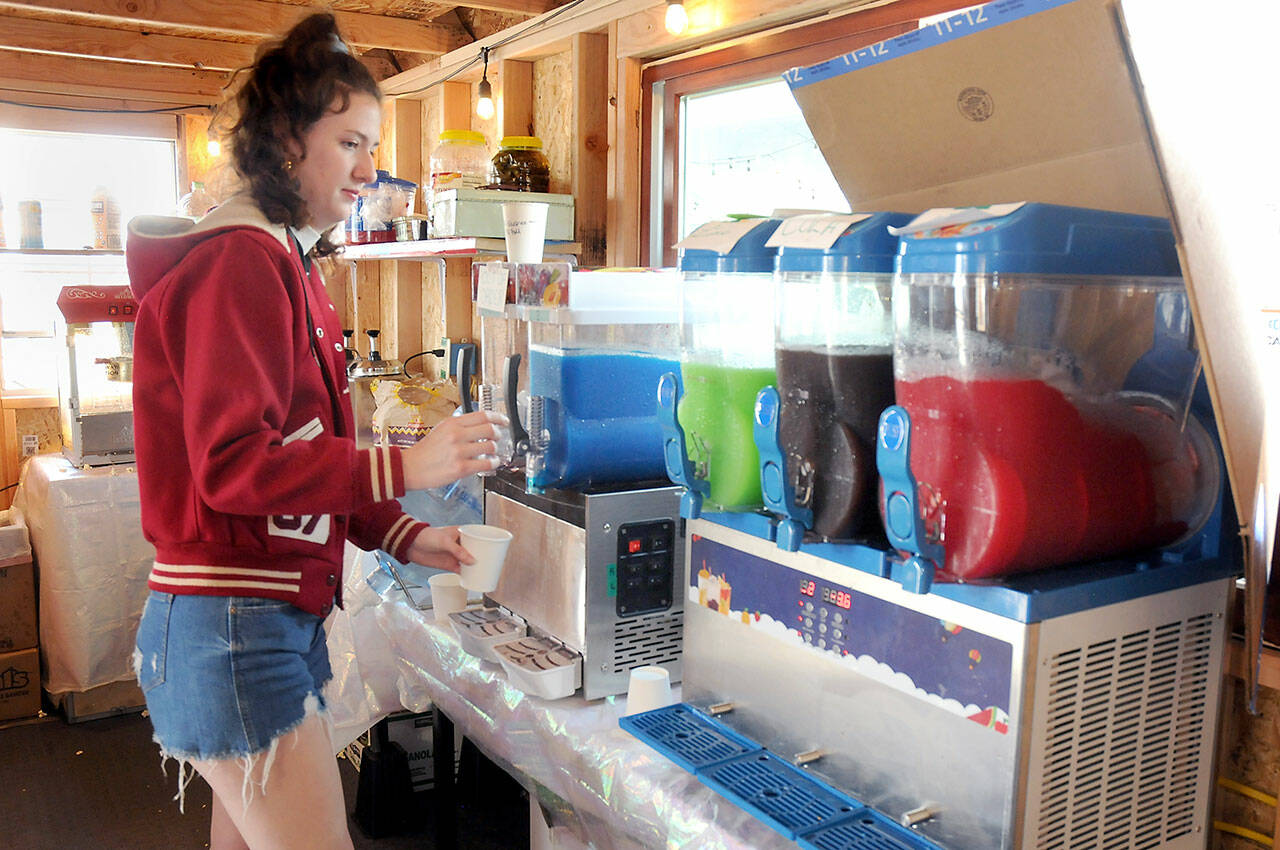 Olympic Skate Village manager Shanzi Cosgrove fills a slushy order at the village’s Snack Shack next to the temporary roller skating rink on Friday in downtown Port Angeles. (Keith Thorpe/Peninsula Daily News)