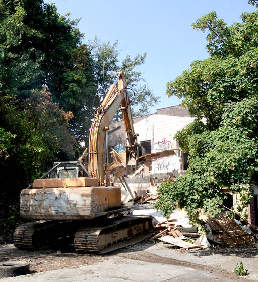 Demolition began Monday morning on the derelict two-story brick building at 204 E. Front St. in Port Angeles. A 300-foot section of Front Street will be shut down while the work is being done, and that could stretch into next week. The developer has said he has plans for an apartment building on the site. (Dave Logan/for Peninsula Daily News)