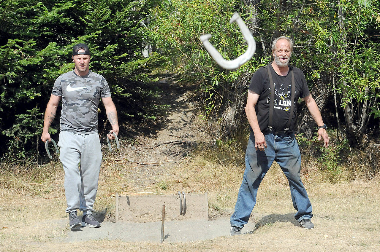 Mark Lingvall, right, throws a horseshoe as his son, Jeremy Lingvall, waits his turn during a game of horseshoes on Tuesday at Lincoln Park in Port Angeles. The Port Angeles men said they were frequent players of the game and bemoaned the fact that only two playable sets of pits still existed at the park. (KEITH THORPE/PENINSULA DAILY NEWS)