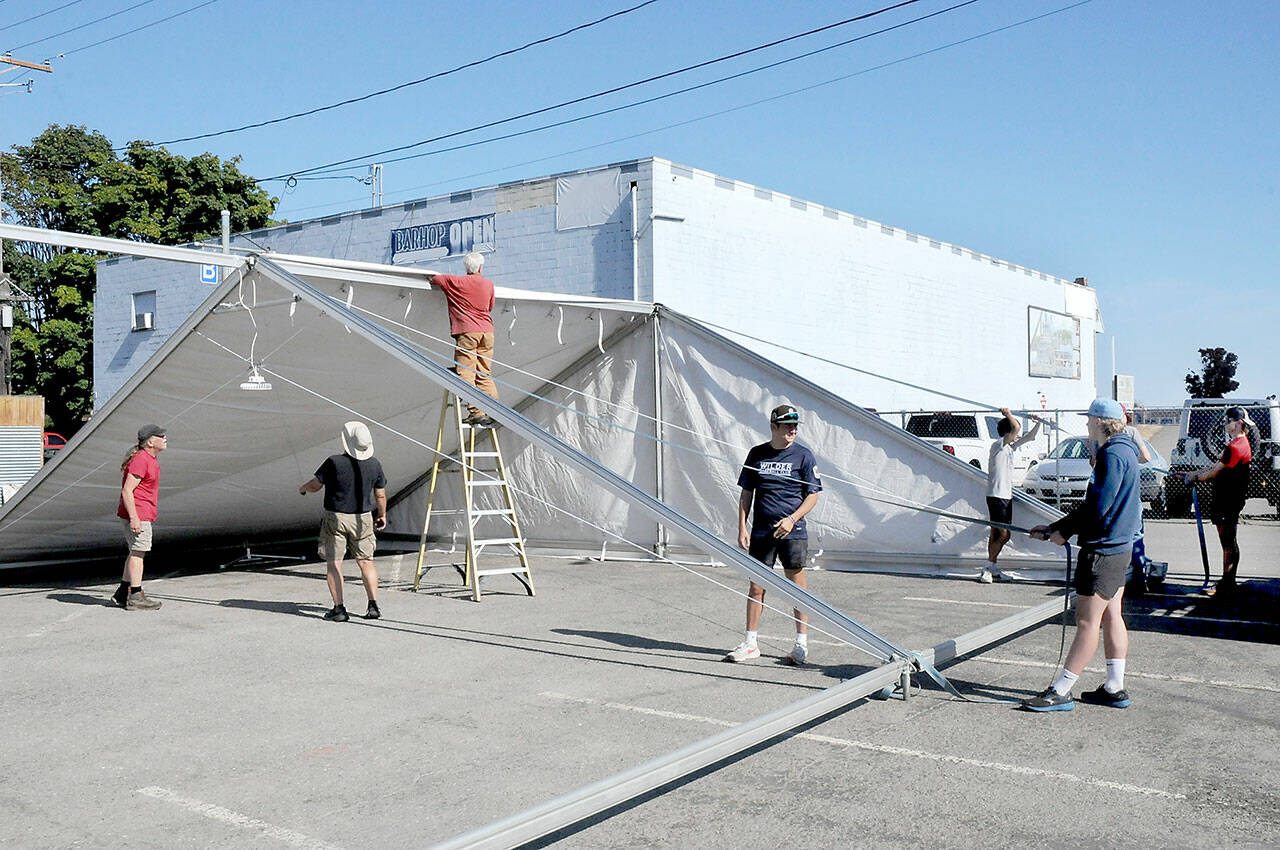 A work crew erects a tent in a city parking lot in the 100 block of West Front Street in downtown Port Angeles on Friday in preparation for Sunday’s First Federal centennial celebration. (KEITH THORPE/PENINSULA DAILY NEWS)
