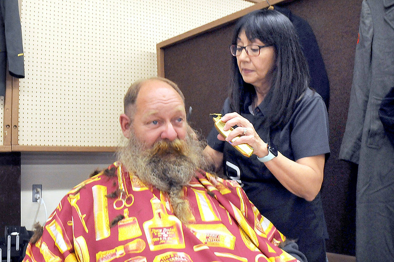 U.S. Navy veteran Brent Brant of Port Hadlock gets a haircut from Susan Gile, owner of Benny’s Barbershop in Sequim, during Thursday’s Port Angeles Stand Down at the Clallam County Fairgrounds. The event was designed to provide direct services and connect veterans to a variety of assistance organizations, as well as offer clothing, medical services and a meal. (Keith Thorpe/Peninsula Daily News)