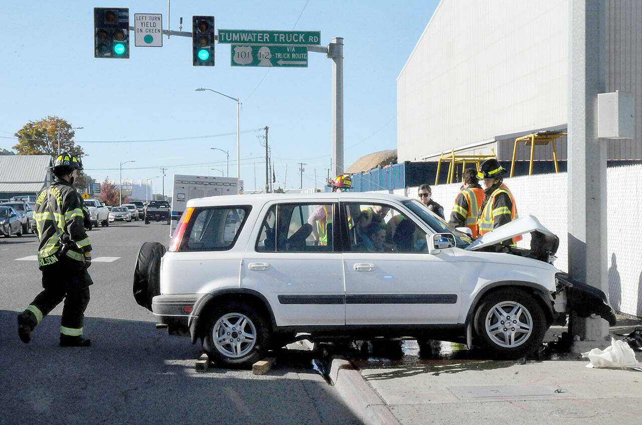 Port Angeles police and rescue workers assist the driver of a vehicle that crashed into a traffic light support pole at Marine Drive and the Tumwater Truck Route at abut 3:30 p.m. Thursday. No more information was available as of Friday. (KEITH THORPE/PENINSULA DAILY NEWS)