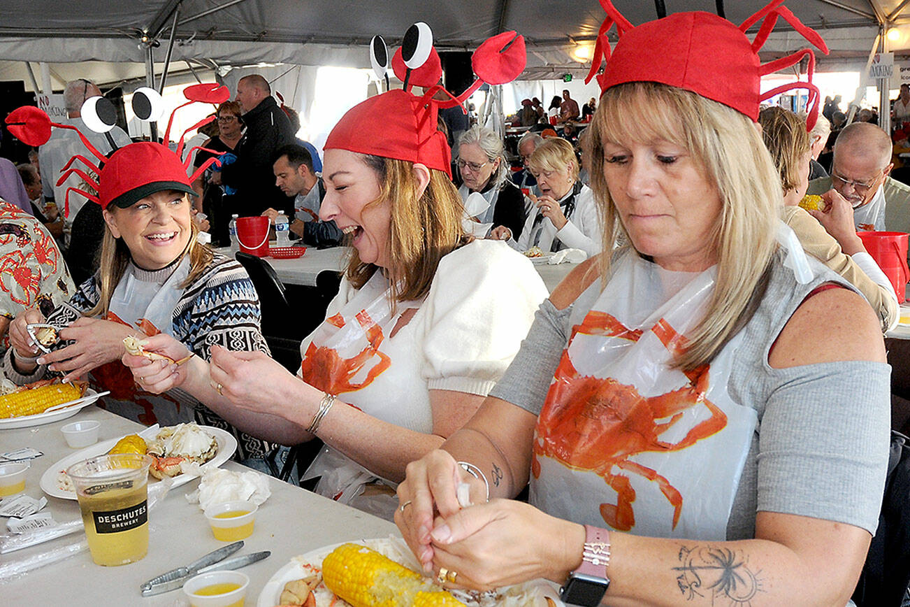 KEITH THORPE/PENINSULA DAILY NEWS
Dungeness Crab and Seafood Festival-goers, from left, Shannon Johnson and Krista Campbell, both of Victoria, and Tammi Donison of Saanich, B.C., enjoy crab dinners while adorned with crustacean hats during Friday's opening day. The three-day festival, which continues today and Sunday, features a variety of seafood, music and other activities in downtown Port Angeles.