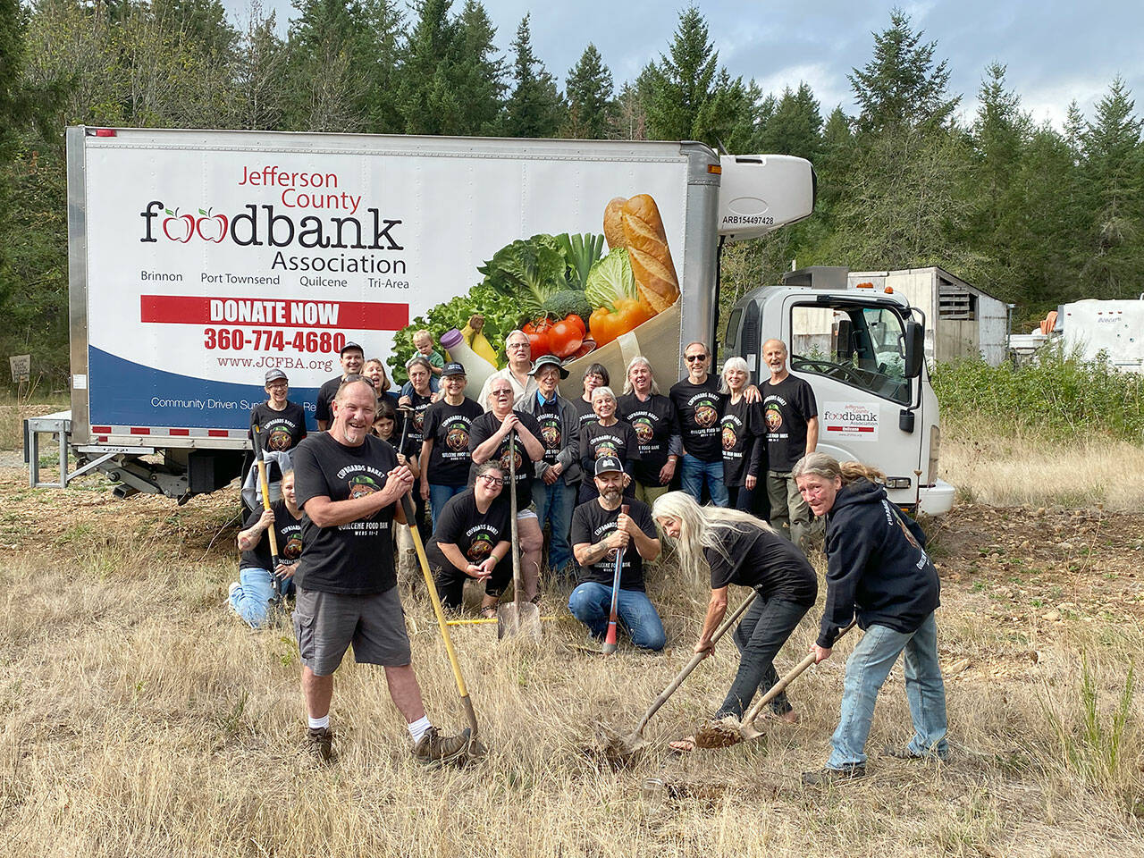 Quilcene Food Bank volunteers look on as Todd Nickerson, left, Ann Kittredge, center, and Leslie Tippins, right, break ground for a new Quilcene Food Bank at 161 Herbert St. in downtown Quilcene. (Keith Neyer)