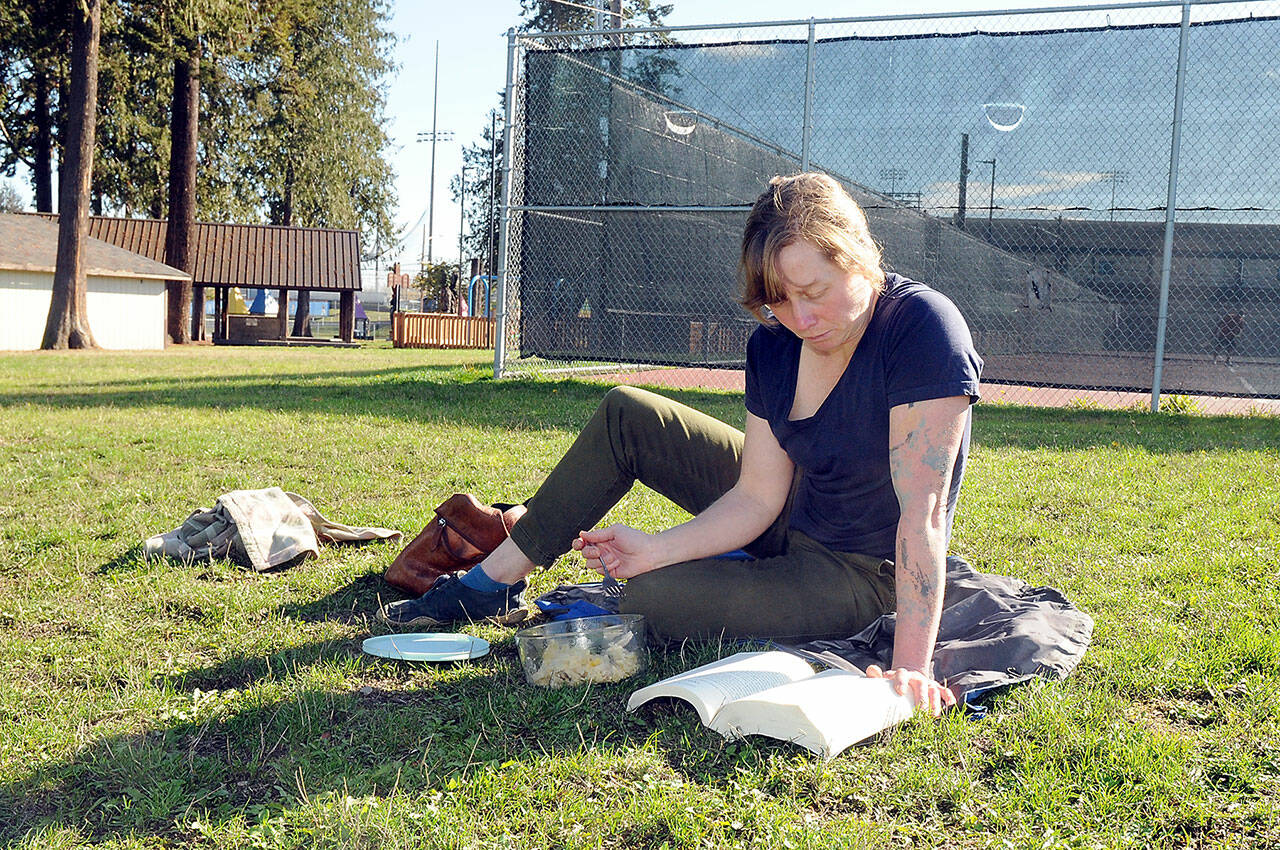 Kellie Baker of Port Angeles enjoys a warm autumn day to eat lunch with a book at Erickson Playfield in Port Angeles on Wednesday. Mostly dry conditions are forecast for much of the region through the weekend with wetter weather expected to return by early next week. (Keith Thorpe/Peninsula Daily News)