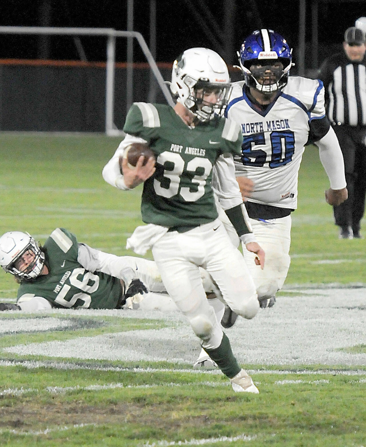 Port Angeles’ James Browning (33) rushes from the backfield chased by North Mason’s Ryan Wright as Port Angeles’ Tanner Flores (56) looks on from behind on Friday night in Port Angeles. (KEITH THORPE/PENINSULA DAILY NEWS)