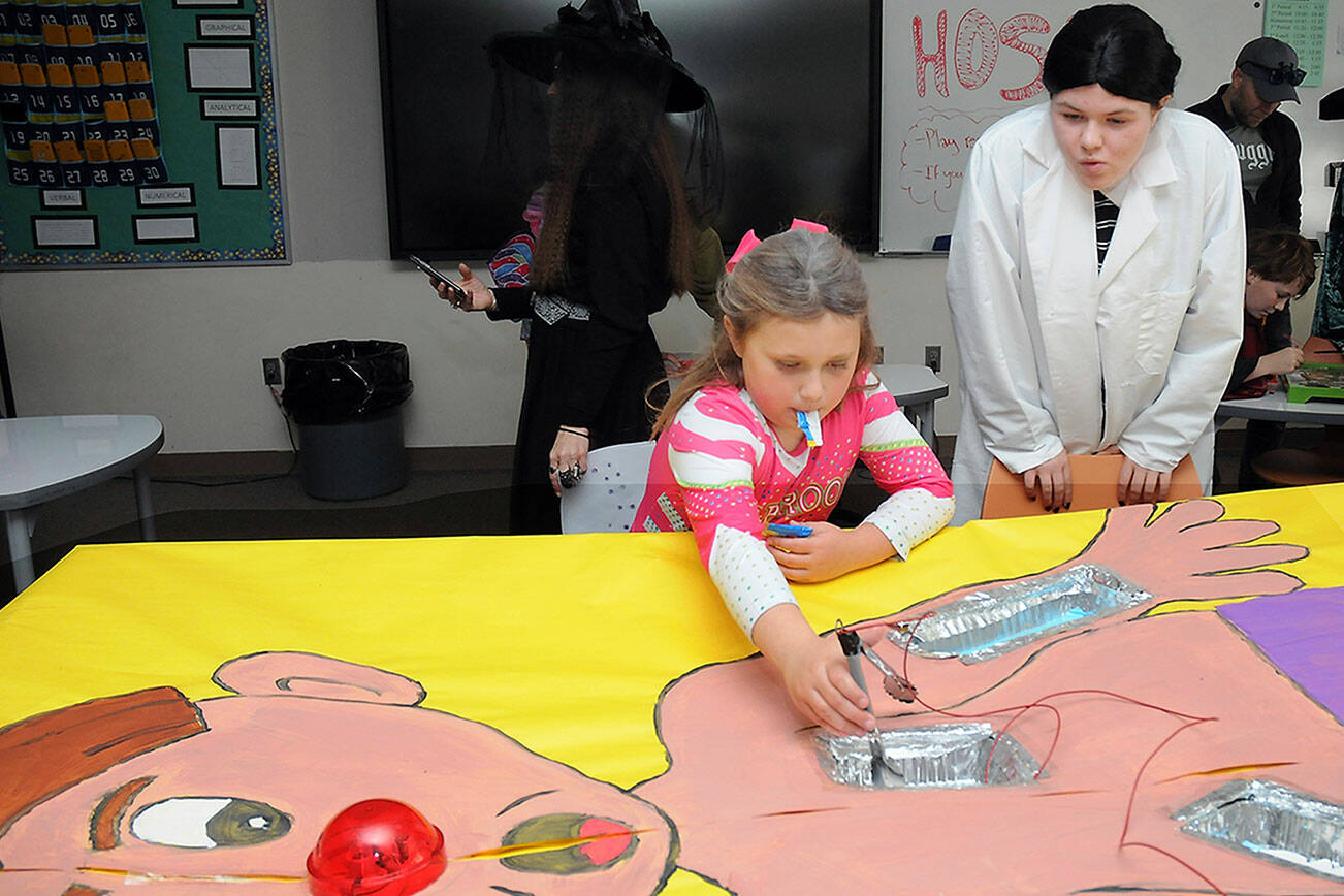 Sonnie Fountain, 8, of Sequim plays an oversized version of the Operation game under the direction of Sequim High School freshman Lillian Anderson during Saturday’s Haunted Hallways holiday event at the school. Haunted Hallways featured a portion of the school set aside for a variety of Halloween games and attractions hosted by students as a benefit for the Sequim Food Bank. (Keith Thorpe/Peninsula Daily News)