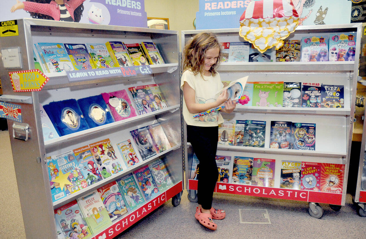 Accasia Anderson, 7, a second-grade student at Greywolf School in Sequim, examines a book for sale on Saturday at the school’s Holiday Bazaar. The event, hosted by the Sequim Elementary Parent Teacher Association, spotlighted the work of more than 50 vendors, including crafts made by students, along with a Scholastic Book Fair. (Keith Thorpe/Peninsula Daily News)