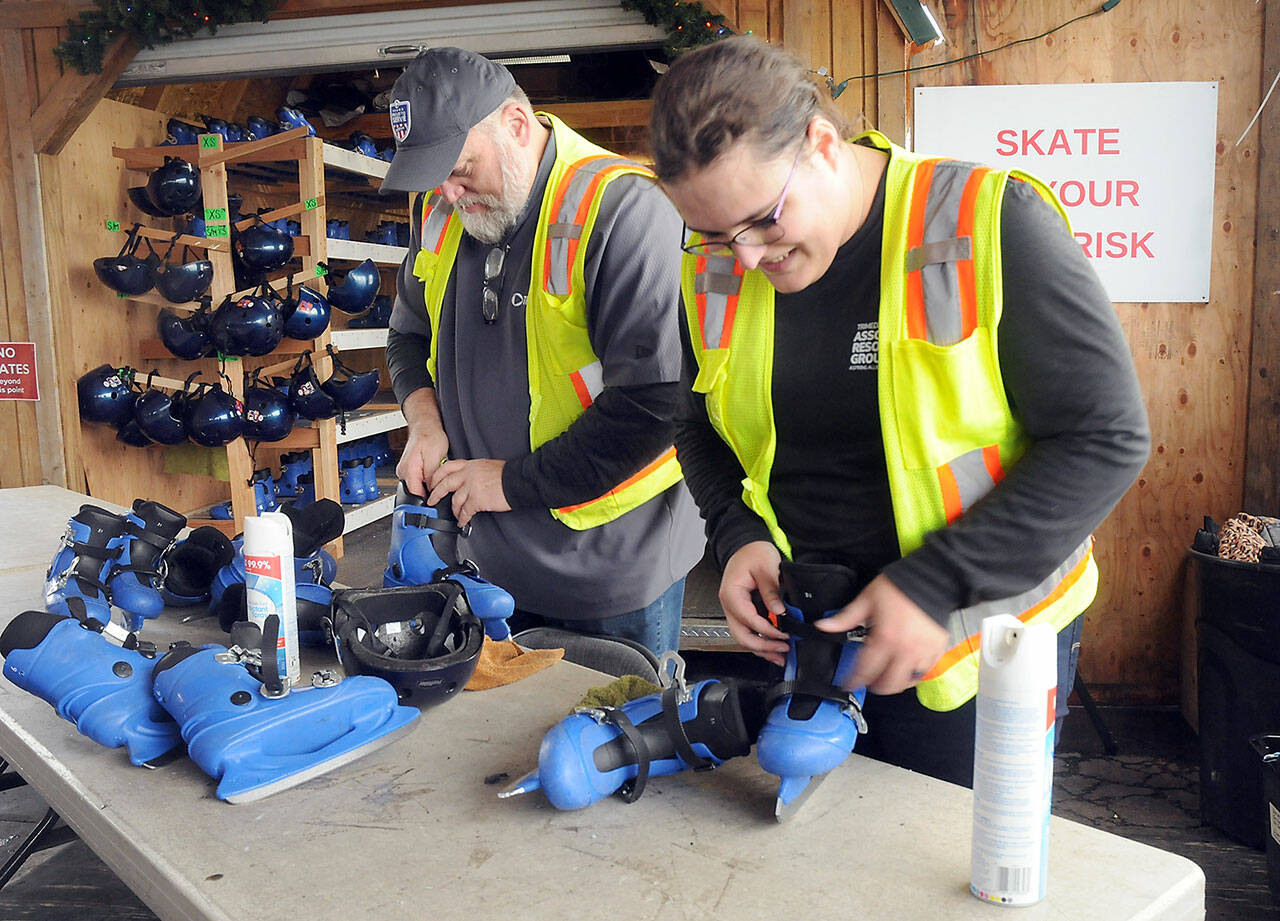 Port Angeles Winter Ice Village volunteers Rich Johnson, left, and Sarah Fixter check in used ice skates on a busy Friday afternoon skate session. (KEITH THORPE/PENINSULA DAILY NEWS)