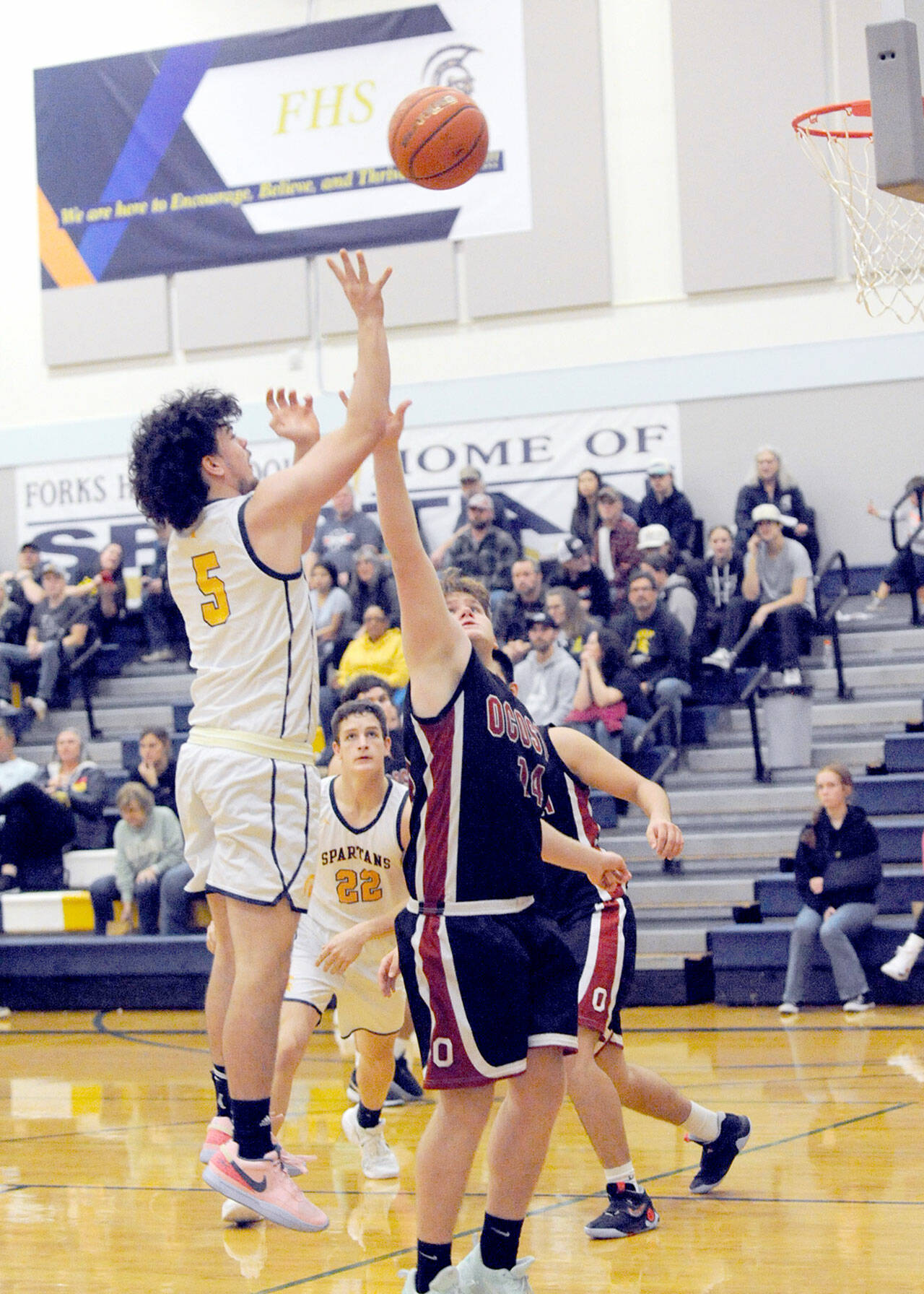 Forks’ Landin Davis puts up a shot over Ocosta’s Kayden Turner while Forks’ Brody Lausche looks on. (Lonnie Archibald/for Peninsula Daily News)