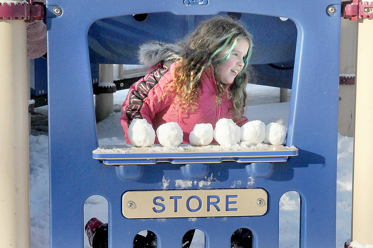 KEITH THORPE/PENINSULA DAILY NEWS 
Madrona Villella, 7, of Port Angeles looks out from a pretend storefront lined with snowballs at the children's playground at Shane Park on a chilly Friday in Port Angeles. The youngster braved single-digit wind chills for a chance at a snow day in the park.