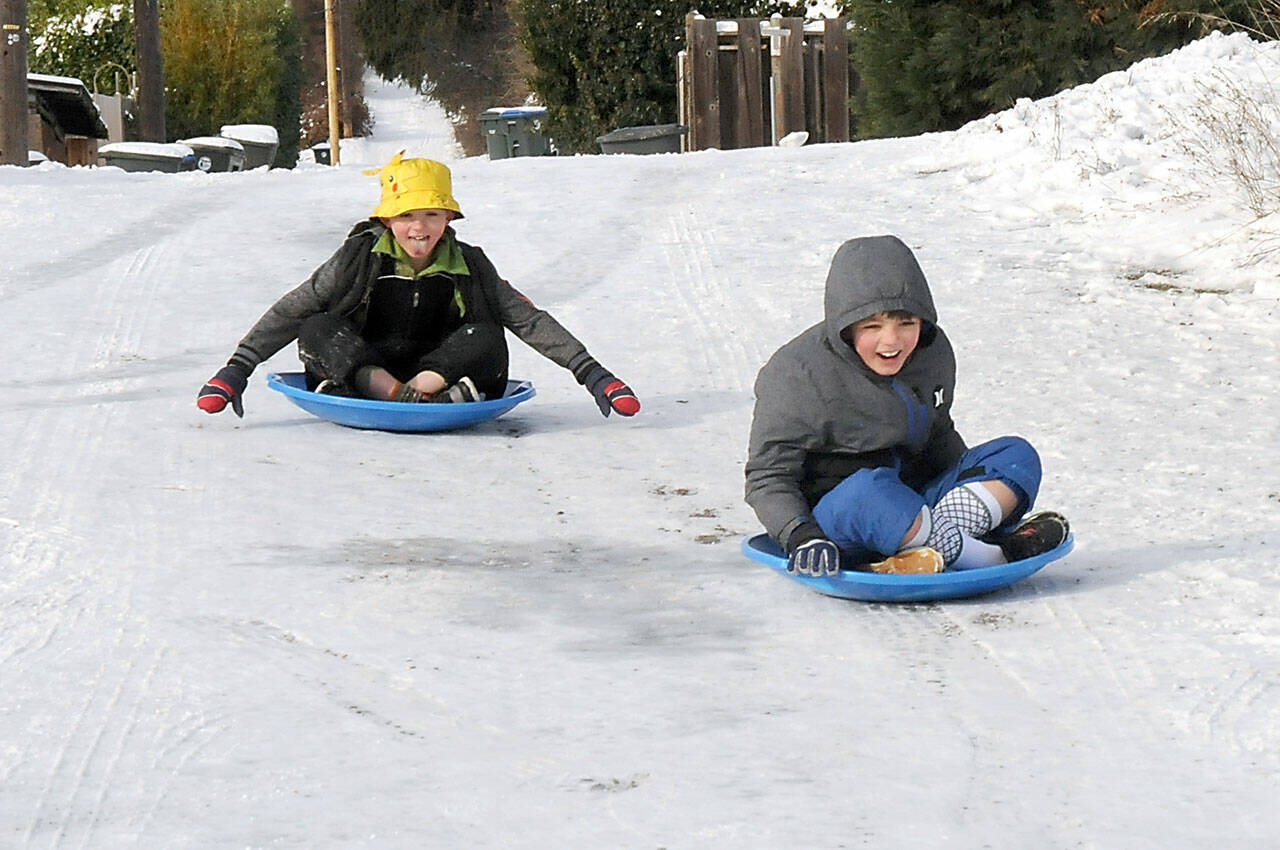 Cameron Torres, 8, left, and his brother, Steven Torres, 9, slide their way down a frozen alley behind their home near 11th and C streets in Port Angeles on Saturday. The youngsters braved temperatures in the 20s and wind chills in the teens in pursuit of some gravity-assisted entertainment. (Keith Thorpe/Peninsula Daily News)