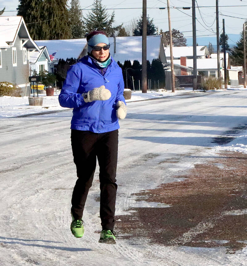 Katherine Hennessy of Port Angeles goes out for a morning jog on Cedar Street on upper Pine hill in Port Angeles on Tuesday. She said the cold and snowy weather doesn’t deter her from training for future distance runs. (Dave Logan/for Peninsula Daily News)