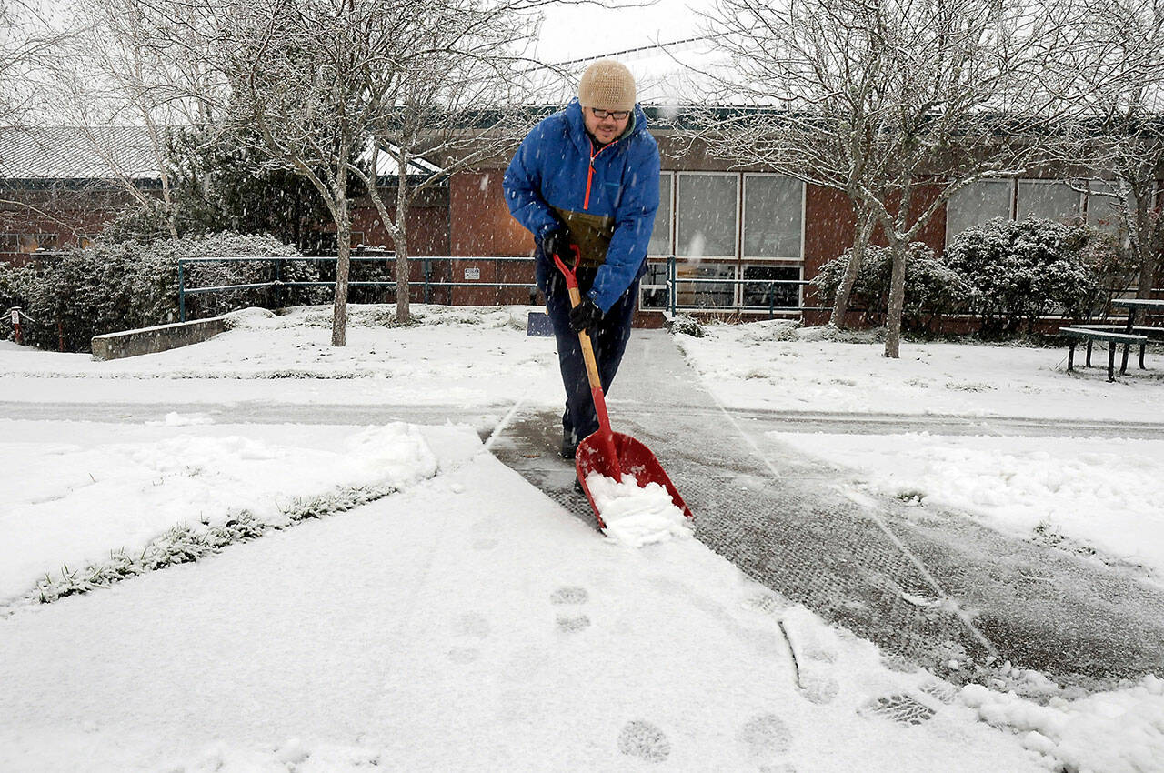 Noah Glaude, executive director of the North Olympic Library System, shovels snow from the front sidewalk at the Port Angeles Public Library after a fast and furious band of snow showers rolled across Port Angeles on Wednesday morning. (KEITH THORPE/PENINSULA DAILY NEWS)