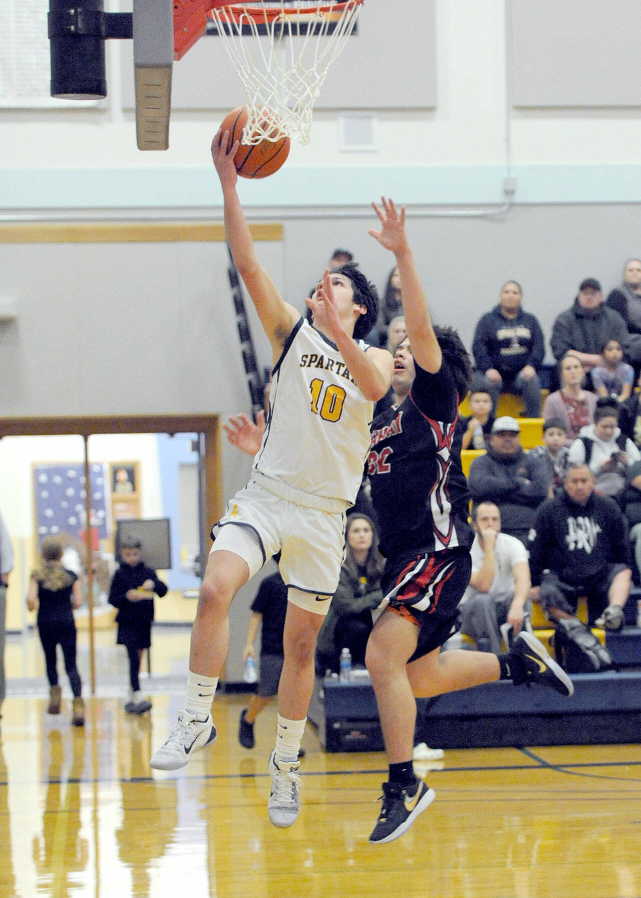 Forks’ Dylan Micheau (10) scores over Neah Bay’s Mathias Greene Monday evening in Forks. (Lonnie Archibald/for Peninsula Daily News)