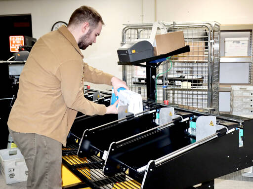 Dave Logan / for Peninsula Daily News
Ryan O’Hara, a Clallam County election assistant, grabs a bundle of 83 ballots that had gone through the first step of validation in the electronic sorting machine after arrival to election headquarters in the basement of the Clallam County Courthouse on Election Day.