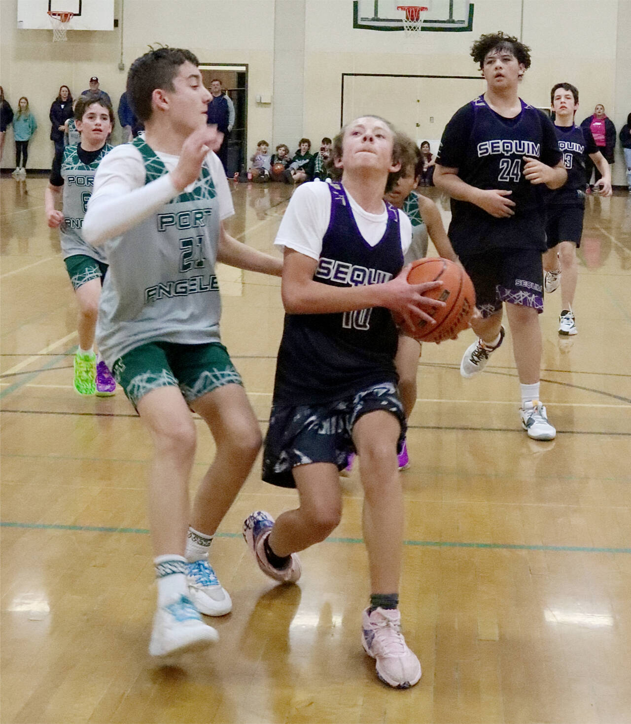 The President’s Day Tournament sponsored by Ruddell Auto held in Port Angeles on Saturday and Sunday featured fourth- through eighth-grade teams, some of which came from as far away as Mount Vernon and Blaine. A total of 30 teams played in the tournament held at Port Angeles High School and Roosevelt Elementary. Here, Sequim seventh-grader #10 Aayden Soiseth (10) drives to the basket guarded by Port Angeles’s sixth-grade team member Payton Strohauer (21). Sequim won the game 35-23. The top two finishers in each division qualified for the Washington State Middle School Basketball Championship to be held in Spokane in March. (Dave Logan/for Peninsula Daily News)