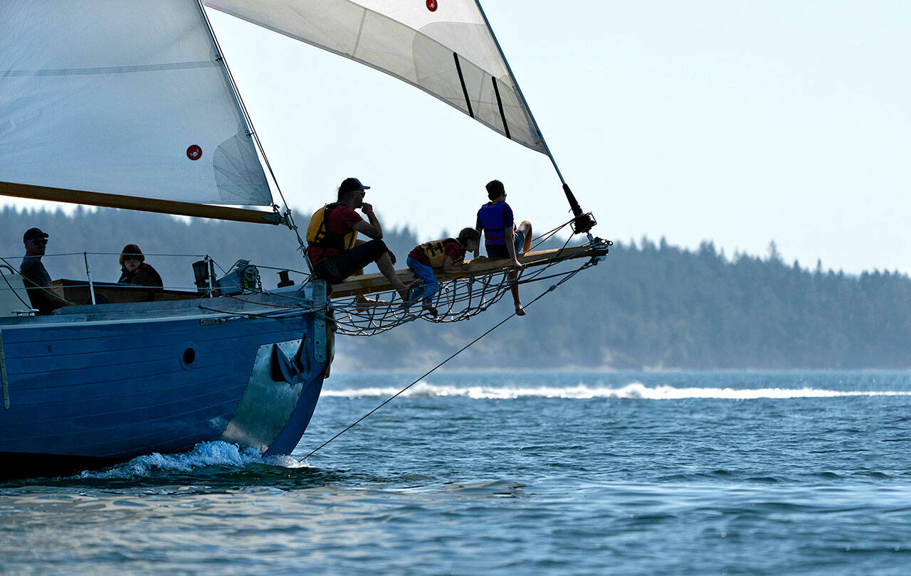 A perch on the bowsprit affords these spectators a wide open view of competing boats in a previous yea’s regatta on Port Townsend Bay. (Steve Mullensky/for Peninsula Daily News)