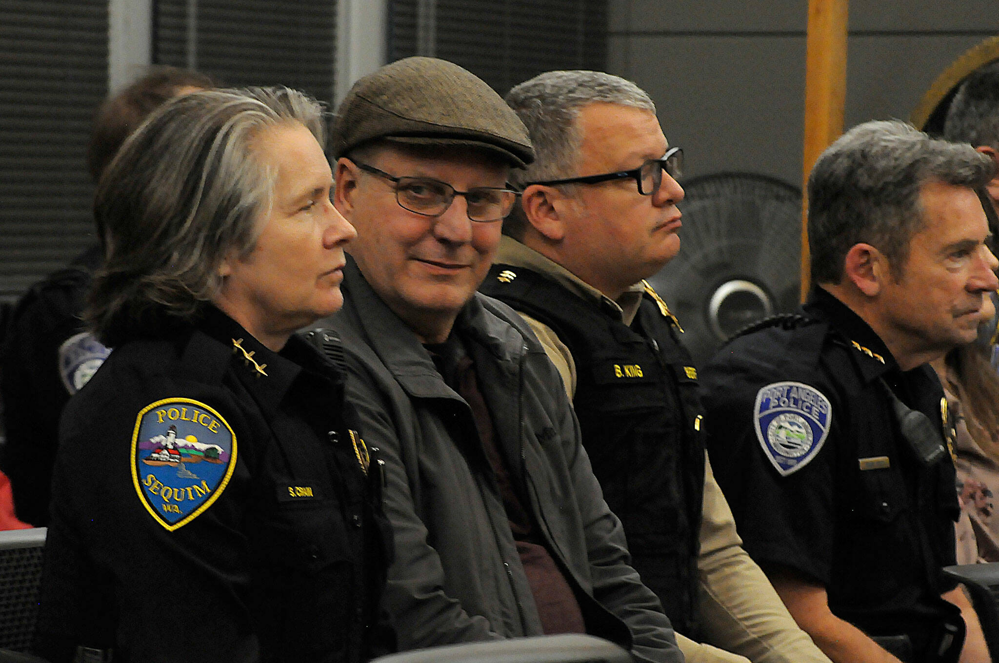 Sequim Police Chief Sheri Crain listens to a proclamation at the Feb. 26 Sequim city council meeting as her husband Pat smiles with pride in her during the ceremony. Next to Pat is Clallam County Sheriff Brian King and, to his right, Port Angeles Police Chief Brian Smith. (Matthew Nash/ Olympic Peninsula News Group)