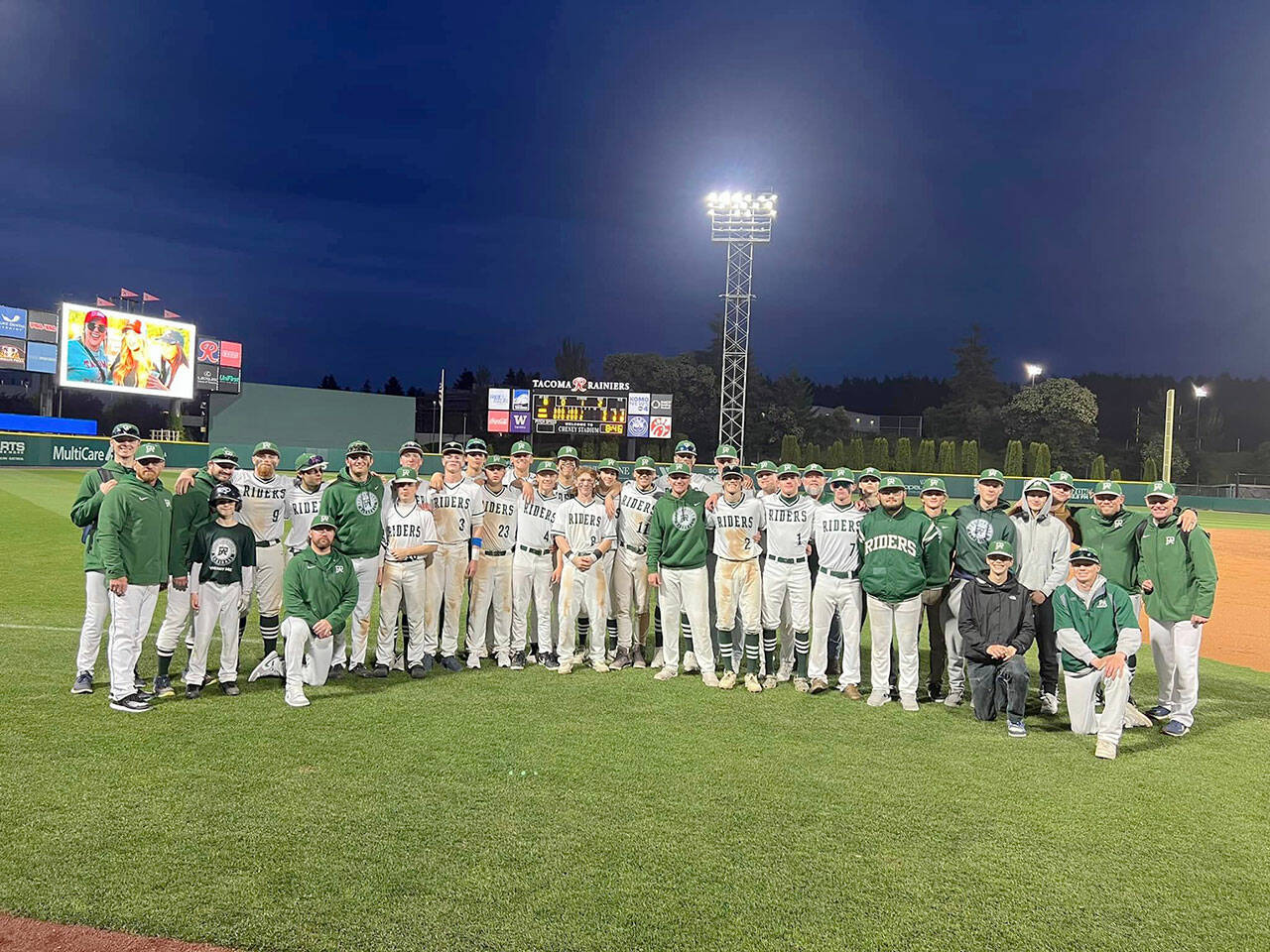 Port Angeles baseball players and coaches celebrate with a team photo on the field at Cheney Stadium after beating King’s 6-5 Wednesday night in the Roughriders’ regular season finale.