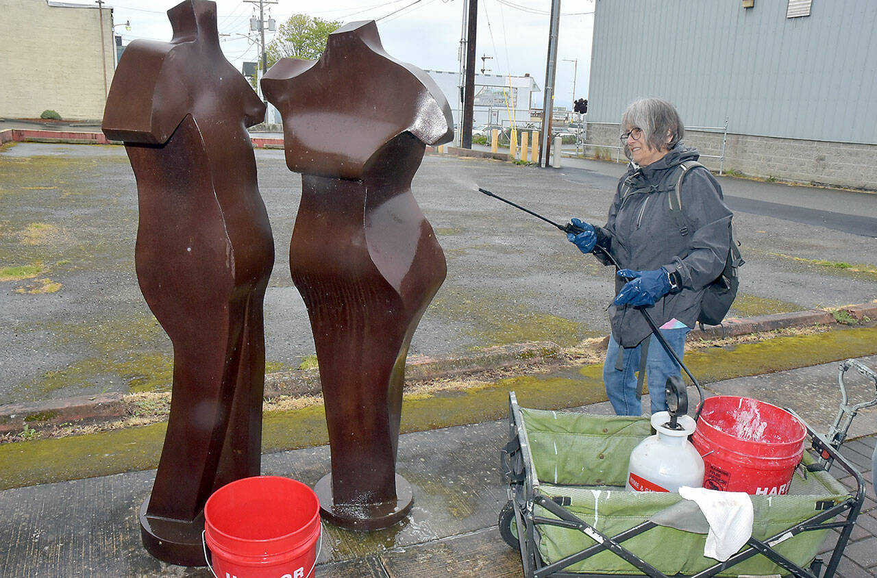 Midge Vogan of Port Angeles sprays cleaner on a pair of sculptures in the 100 block of North Laurel Street in downtown Port Angeles on Saturday as part of the fourth annual Big Spring Spruce Up, sponsored by the Port Angeles Chamber of Commerce. Dozens of volunteers spread out over the downtown area to help beautify the city. (Keith Thorpe/Peninsula Daily News)