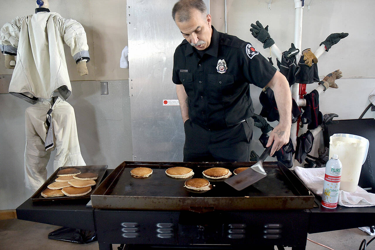 Port Angeles Fire Department community paramedic Brian Gerdes flips pancakes during Saturday’s annual breakfast on Saturday at the fire hall. The event, hosted by the fire department and auxiliary, was a fundraiser for department scholarships and relief baskets. (Keith Thorpe/Peninsula Daily News)