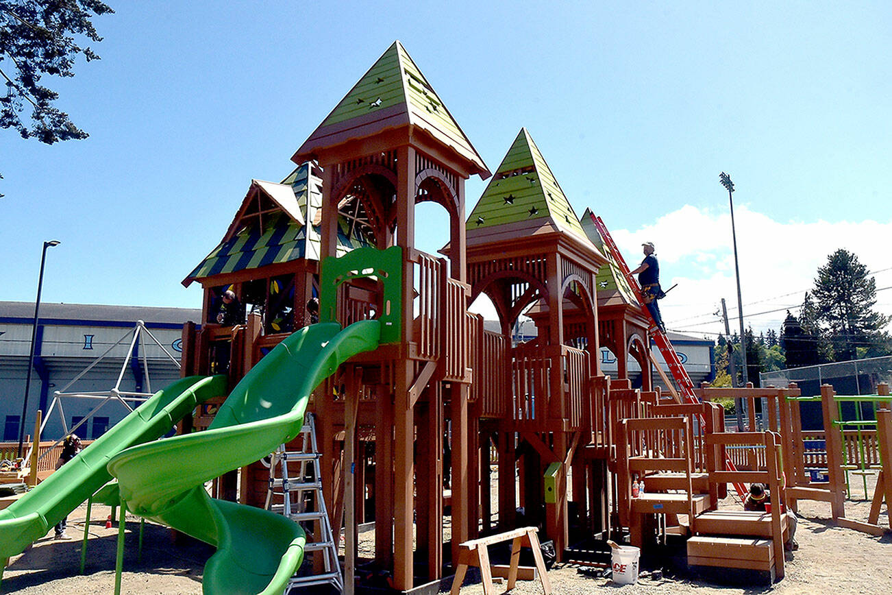 Volunteers work to construct the main play structure of the Dream Playground at Erickson Playfield in Port Angeles on Sunday, the last day of a five-day community build to replace play equipment destroyed by arson in December. The playground, built entirely with donated labor, will be substantially complete with primarily detail work and play surface installation still to come. (Keith Thorpe/Peninsula Daily News)