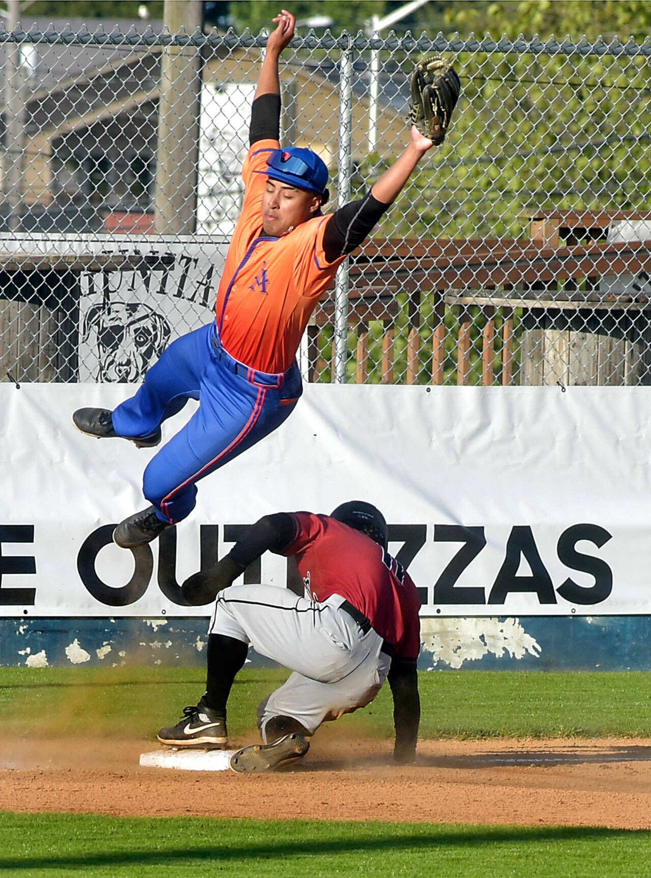 KEITH THORPE/PENINSULA DAILY NEWS Lefties third baseman Roberto Nunez leaps for a wild throw as Redmond baserunner Charlie Deggeller makes it to the bag on Wednesday’s season opener at Port Angeles Civic Field.