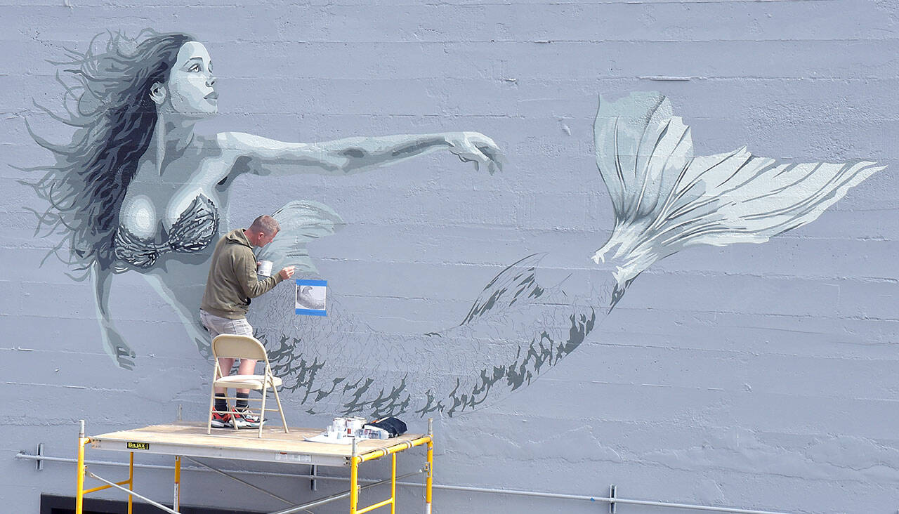 Artist Christopher Keywood of San Diego creates a mermaid mural on the north side of HarborTowne Mall in downtown Port Angeles on Thursday. Keywood, along with the mall’s owner, decided that the blank wall deserved a decoration visible from The Gateway transit center and nearby North Lincoln Street. (Keith Thorpe/Peninsula Daily News)