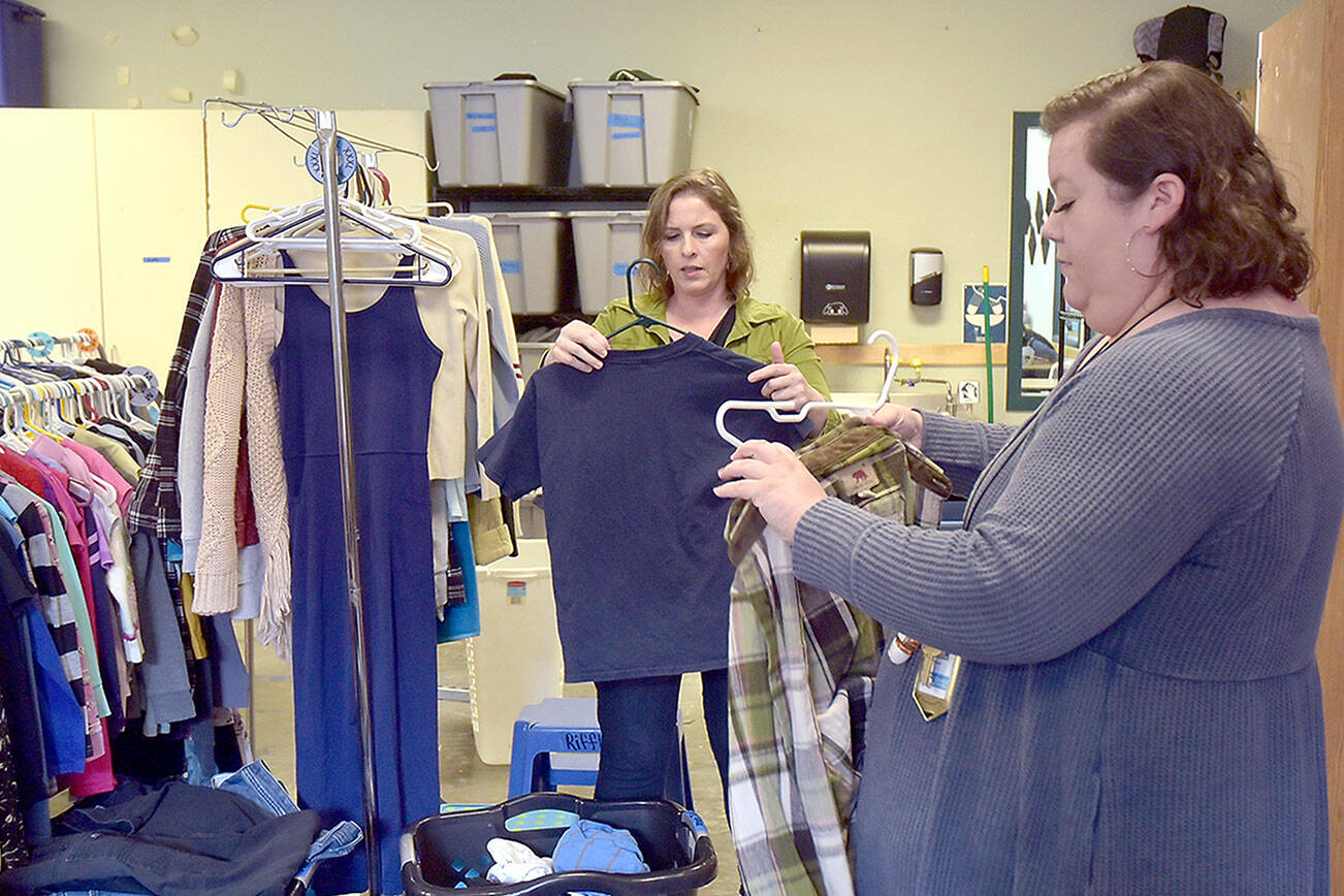 Alicia Scofield, left, and Summer Cooper, family navigators for the Port Angeles School District, sort over donated clothing available to students and their families at the Caring for Kids Clothing Closet located at Lincoln Center. (Keith Thorpe/Peninsula Daily News)