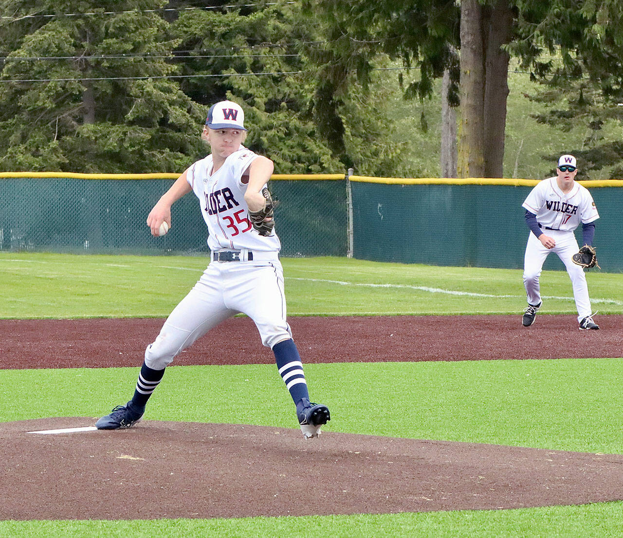 Wilder Senior pitcher Landen Olson of Forks pitches against Narrows 18U on Monday at Volunteer Field with teammate Brayden White (Sequim) at first base. Wilder scored two runs in the ninth but fell just short of a comeback victory in a 7-6 loss. (Dave Logan/for Peninsula Daily News)