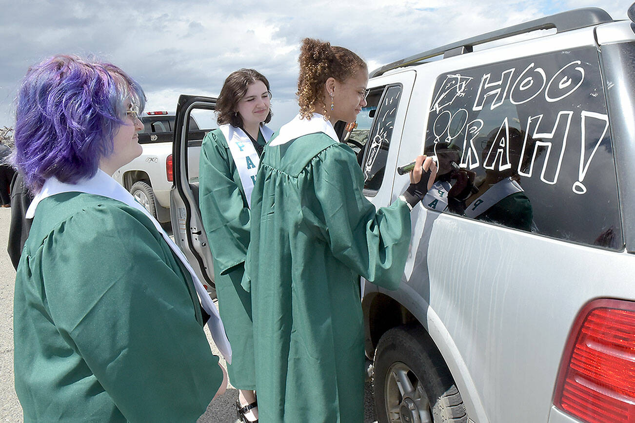 Port Angeles High School graduates, from left, Uri Crawford, Samantha Combs and Jordan McTear, decorate a vehicle in preparation for Friday’s graduation parade from Ediz Hook to the high school. Dozens of adorned cars and trucks carried grads through the streets of Port Angeles as a lead-up to the graduation ceremony that evening at Civic Field. (Keith Thorpe/Peninsula Daily News)