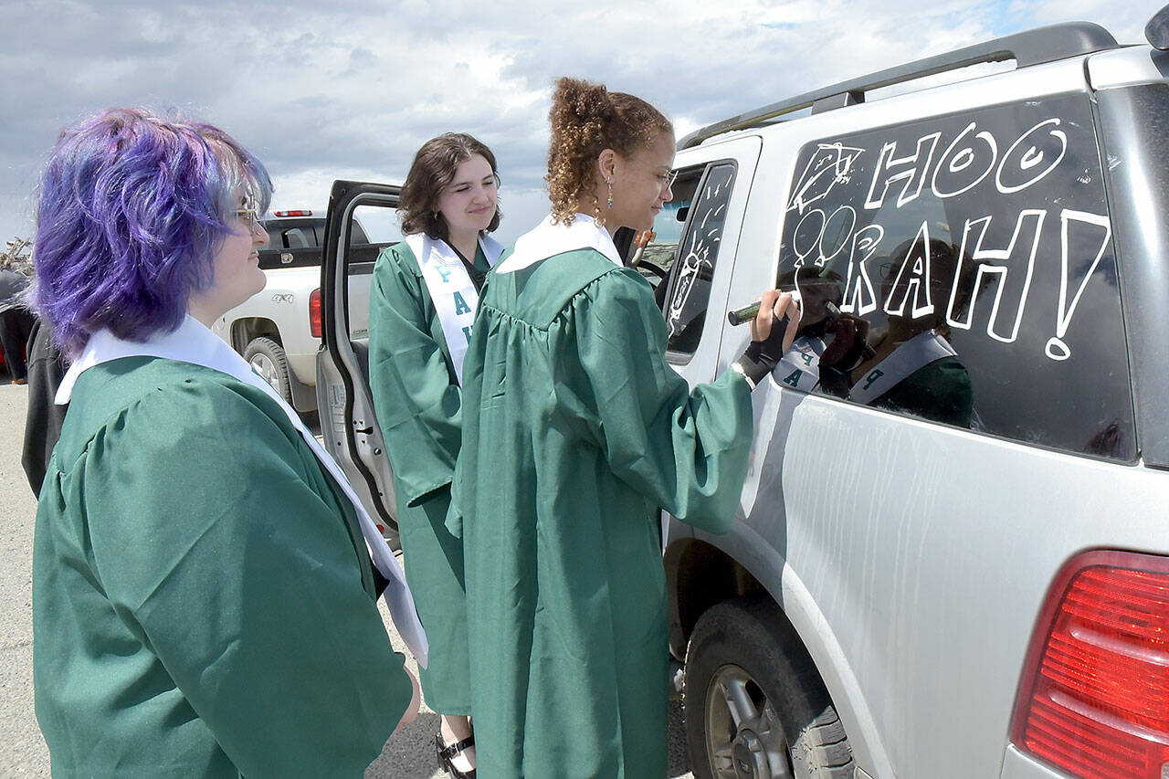 Port Angeles High School graduates, from left, Uri Crawford, Samantha Combs and Jordan McTear, decorate a vehicle in preparation for Friday’s graduation parade from Ediz Hook to the high school. Dozens of adorned cars and trucks carried grads through the streets of Port Angeles as a lead-up to the graduation ceremony that evening at Civic Field. (Keith Thorpe/Peninsula Daily News)