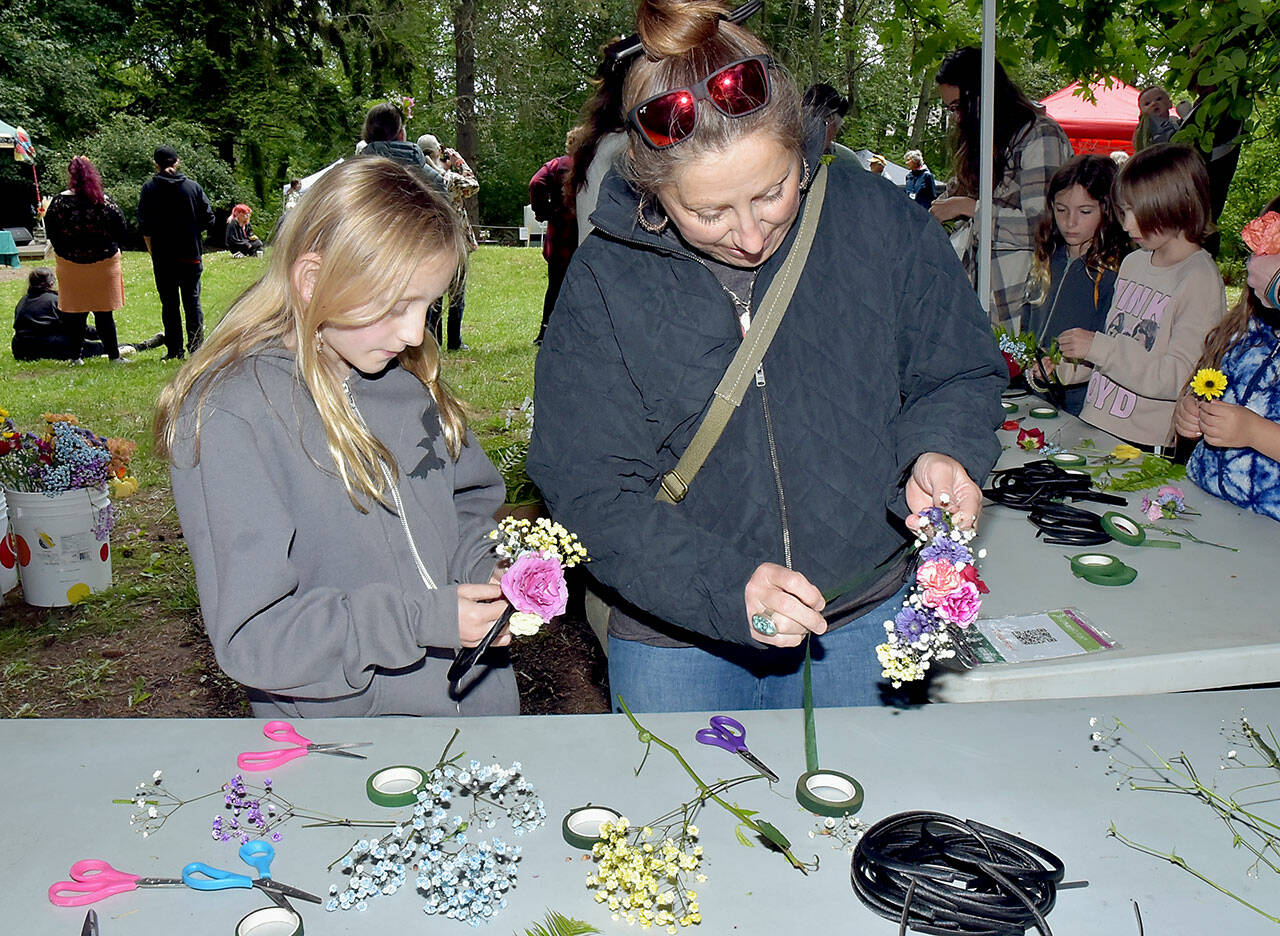 Elora Wilson, 10, and her mother, Eria Wilson of Sequim, create solstice crowns to wear on their heads at a craft table in Webster’s Woods Sculpture Park at the Port Angeles Fine Arts Center during Saturday’s Summertide Solstice Art Festival. The event featured music entertainment, poetry reading, crafts, food and games as a celebration of the upcoming beginning of summer and the longest day of the year. (Keith Thorpe/Peninsula Daily News)