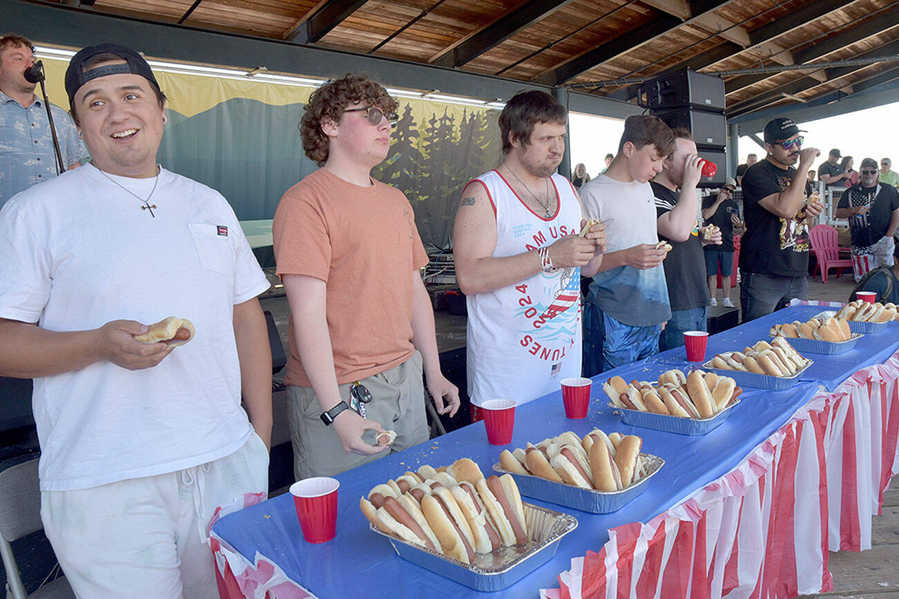 Hot dog eating contestants, from left, Jericho Stuntz of Port Angeles, Lincoln Forrest of Port Angeles, Sebastian Gagnon of Port Angeles, Leo Chouinard of Waupaca, Wisc., Ian Bravender of Port Angeles and Rickie Sanchez of Portland, Ore., chow down on hot dogs during Thursday’s Independence Day contest at Port Angeles City Pier. Stantz won the contest by eating 8 1/2 hot dogs in 10 minutes, earning him a $10 cash card from Swain’s General Store. (Keith Thorpe/Peninsula Daily News)