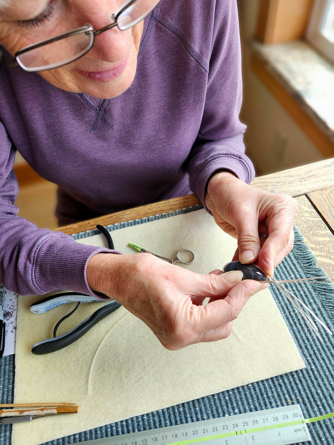 Paulette Hill, a jewelry artist, wire wrapping a Botswana agate cabochon.
Paulette Hill, a jewelry artist, wire wraps a Botswana agate cabochon.