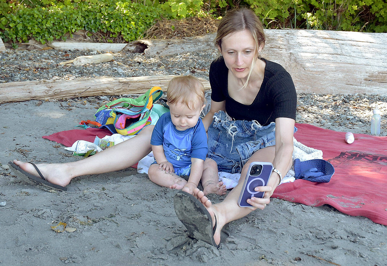 Kara Wolfe of Puyallup and her son, Eli, 11 months, take a selfie on the beach at Freshwater Bay west of Port Angeles on a sunny Saturday. Temperatures in the upper 70s to low 80s across the North Olympic Peninsula found many people looking for ways to beat the heat as summer conditions rolled across the region. (Keith Thorpe/Peninsula Daily News)