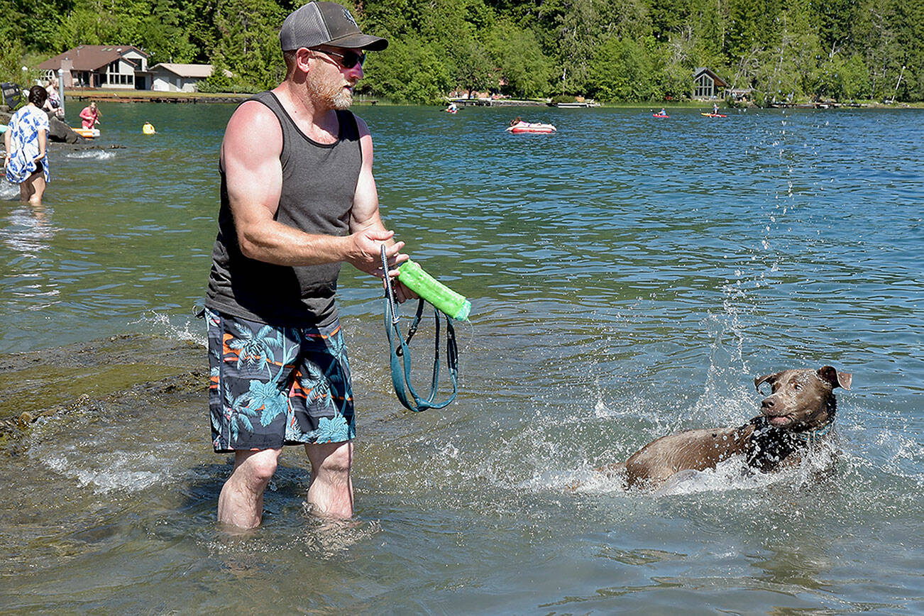 Wrestling coach Rob Gale prepares to toss a floating toy for his dog, Stella, to fetch in the waters of Lake Crescent at Log Cabin Resort in Olympic National Park on Saturday. Summer weather drew hundreds of people to the lake as a way to beat the heat. (Keith Thorpe/Peninsula Daily News)