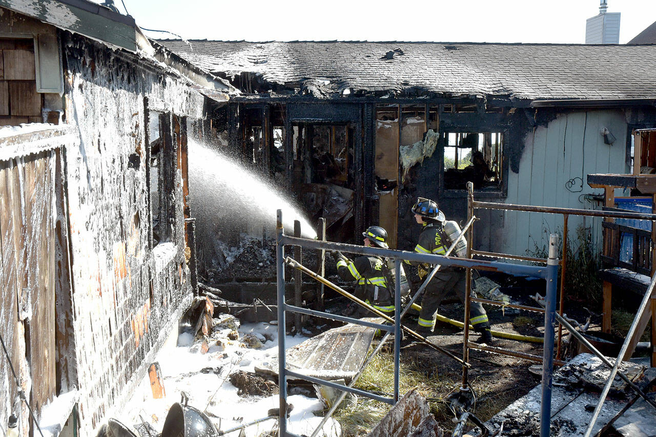 Port Angeles firefighters extinguish hot spots on a fire that gutted a house in the 1600 block of West Sixth Street on Thursday morning. (Keith Thorpe/Peninsula Daily News)